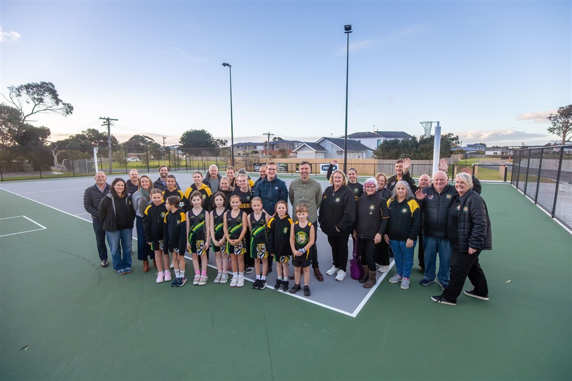 image of group of adults and kids in netball uniform smiling at camera.jpg