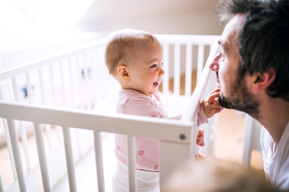 Baby in cot reaching for dad's face.jpg