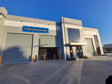 Photograph of grey warehouse with signage 'Victoria's Container Deposit Scheme'