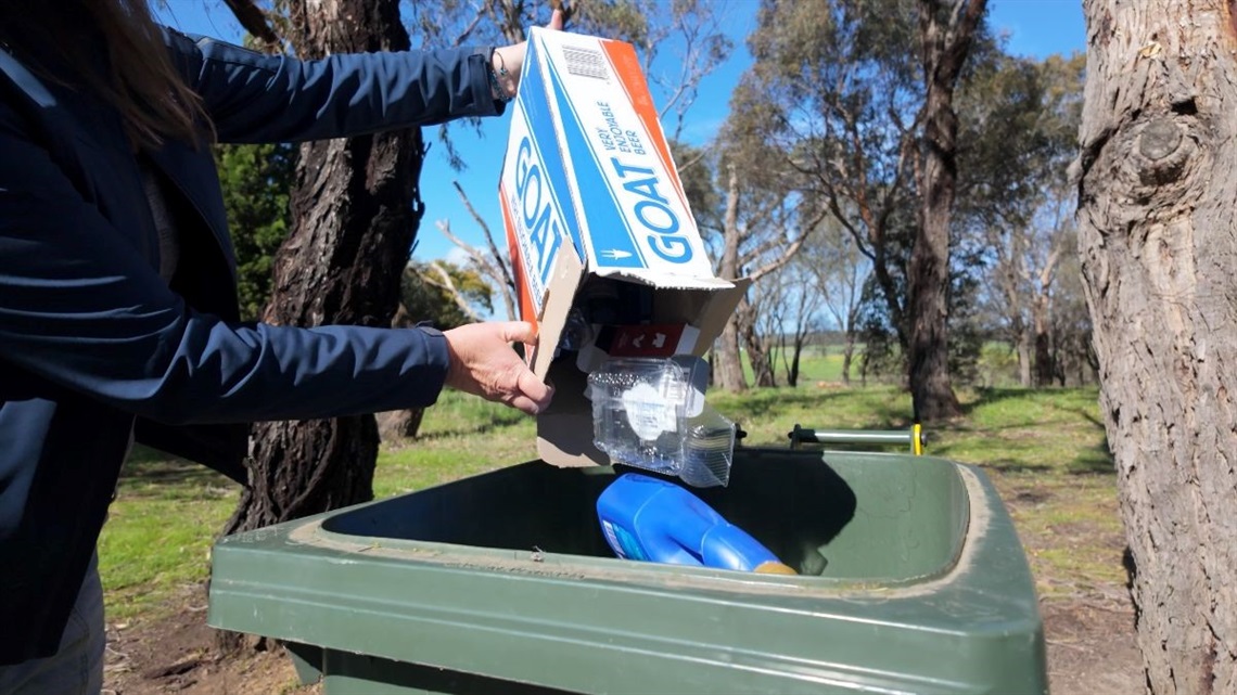 Person tipping recycling items into recycing bin.jpg