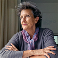 Photograph of Jo looking off to the left, she has short hair and is wearing a long sleeve grey top and a purple scarf