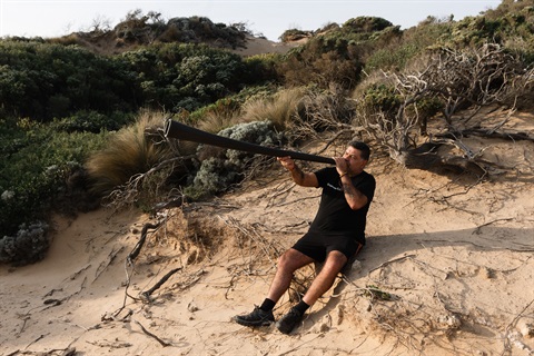 Uncle Lionel playing the yidaki on the sand dunes.