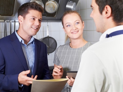 A group of people in a commercial kitchen discussing insurance