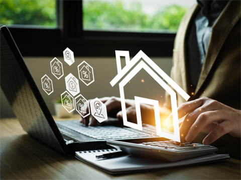Person sitting at a laptop with house and financial symbols in white hovering above it.